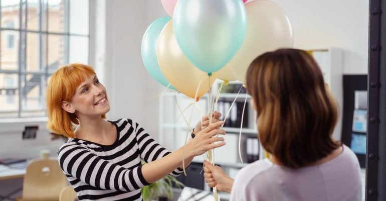 Two female business partners holding balloons