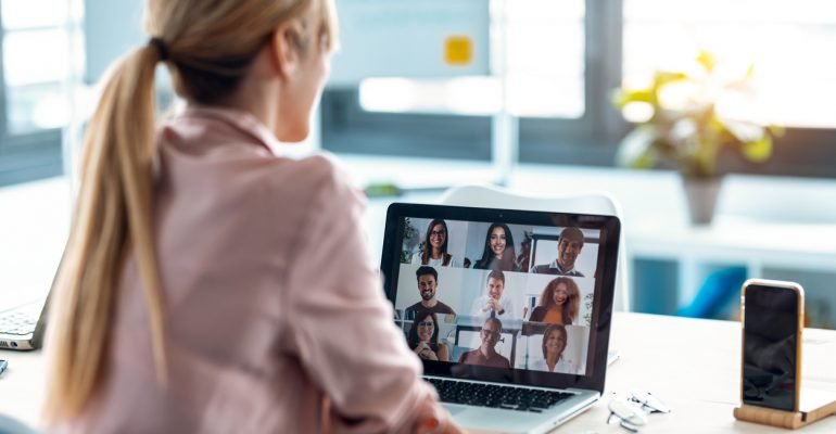 Female employee speaking on video call with diverse colleagues on online briefing with laptop at home.